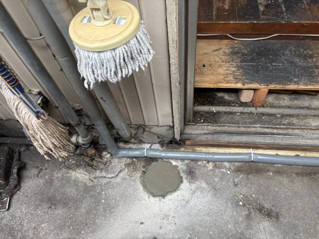 外壁沿いに立ち上げた給水管と床のモルタル復旧跡